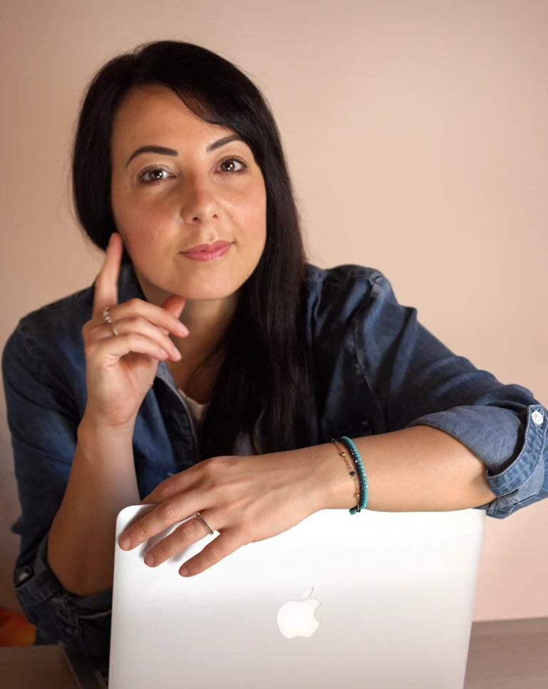 Ritratto di Romina Schipano in camicia di jeans, appoggiata al suo laptop mentre guarda l'obiettivo con un'espressione accogliente, ideale per la presentazione dei servizi di Aiutarelazioni.